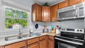 Una cocina con armarios de madera, un microondas de acero inoxidable y un horno.