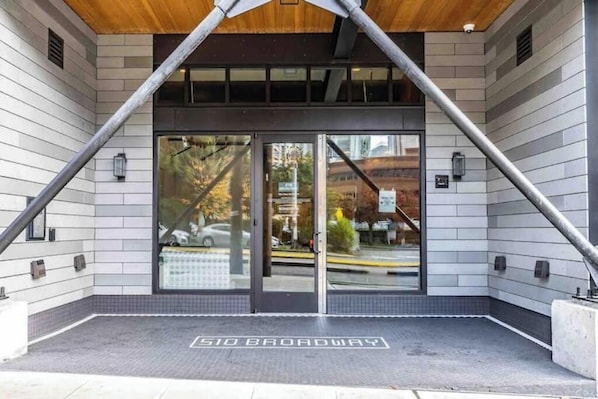 Une entrée d’immeuble avec une porte en verre, une enseigne indiquant « 510 Broadway » et un sol carrelé.