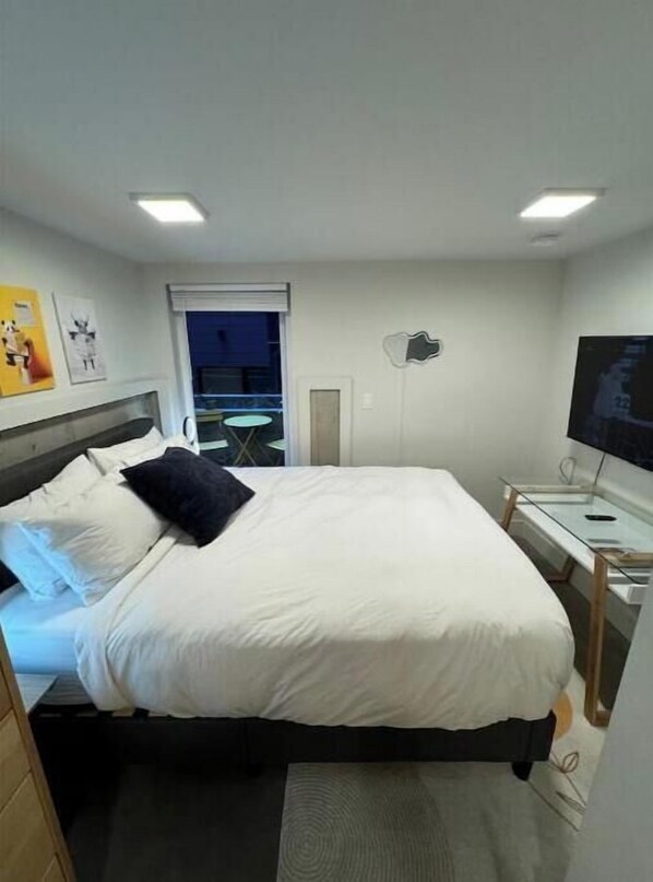 A hotel room with a bed, a desk, a chair, a TV, and a window.