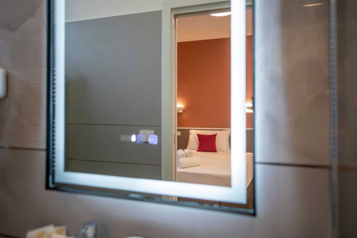 Une chambre d’hôtel avec un lit, un oreiller rouge et une table de chevet avec une lampe.