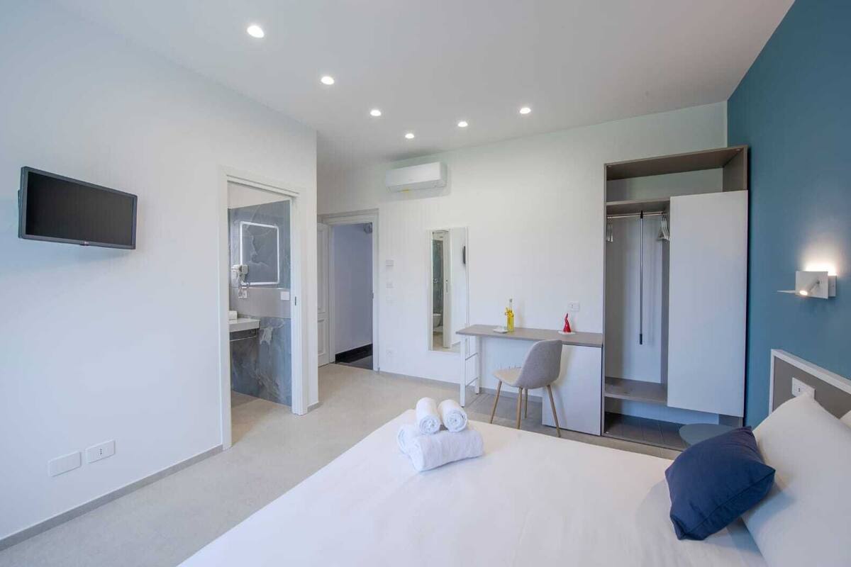 Une chambre d’hôtel moderne équipée d’un lit, d’un bureau, d’une chaise, d’une télévision et d’une salle de bain.
