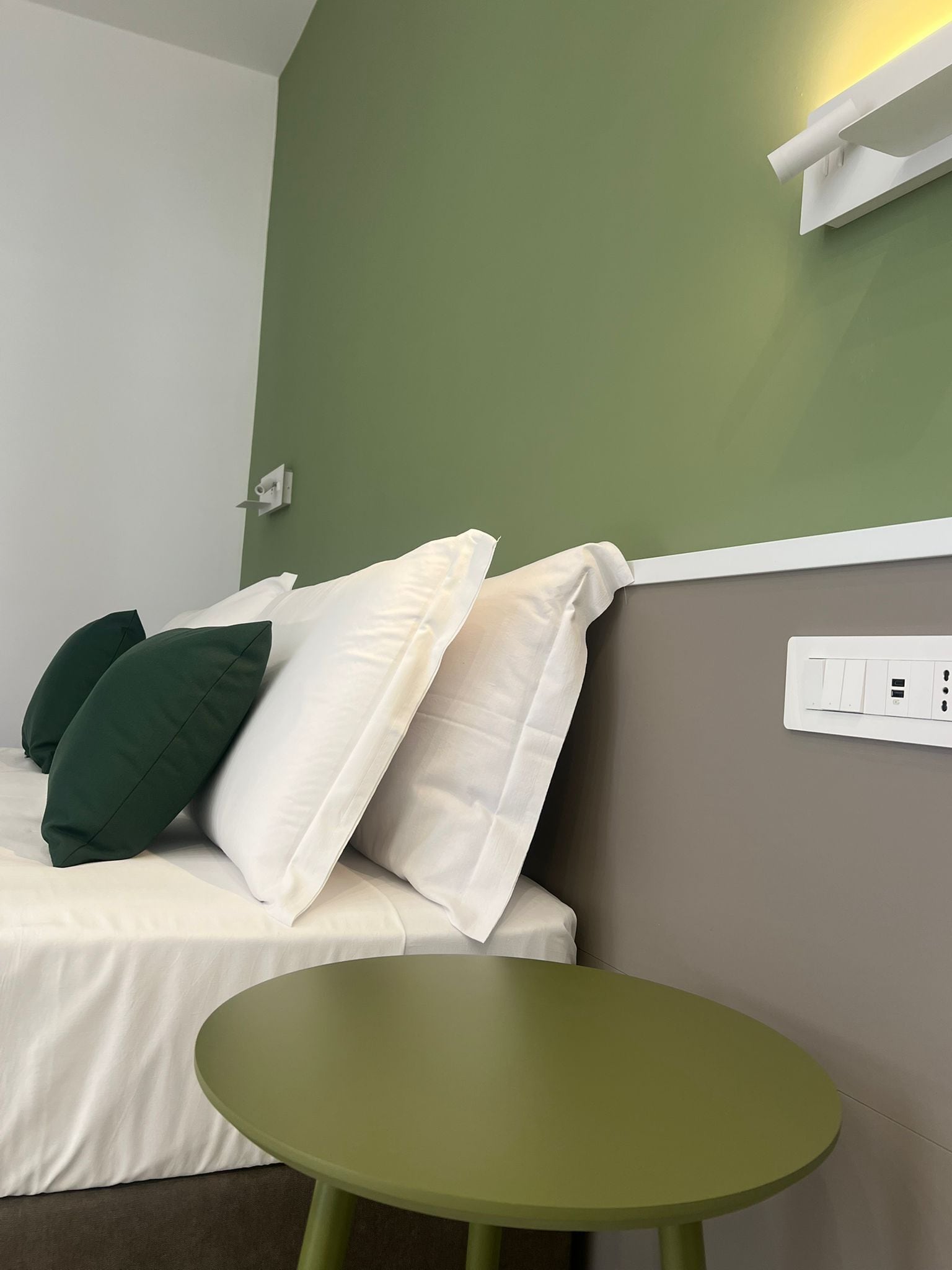 A room with a bed, a green table, and a wall socket.