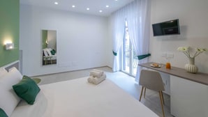 Una moderna camera d'albergo con un letto, una scrivania, una televisione e una finestra con tende.