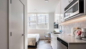 A compact kitchen with a microwave, sink, and a small dining area with a chair and table. - Condotel Broadway-E Jefferson-Close to Convention (Seattle)