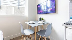 A modern dining area with a table, two chairs, a small potted plant, and a flat-screen TV mounted on the wall. - Cityscape-Condotel-First Hill (Seattle)