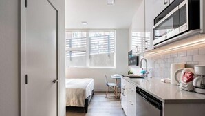 A compact kitchen with a microwave, sink, and a small dining area with a table and chairs. - Cityscape-Condotel-First Hill (Seattle)
