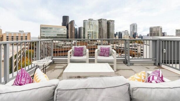 A rooftop terrace with a city view, white outdoor furniture, and a railing. - Cityscape-Condotel-First Hill (Seattle)