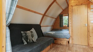 Une chambre mansardée chaleureuse avec un plafond en bois, un canapé, un lit et une armoire.
