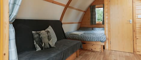 A cozy attic bedroom with a wooden ceiling, a sofa, a bed, and a wardrobe.