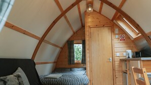 Un intérieur chaleureux et rustique, avec un lit en mezzanine, un canapé et un coin cuisine.