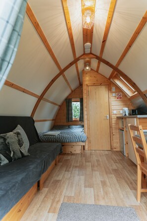A cozy, wooden interior with a loft bed, a sofa, and a kitchenette.