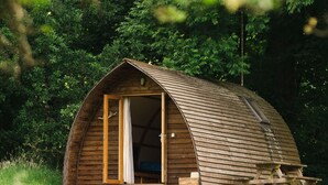 Une cabane en bois avec un toit incurvé, une grande porte ouverte et un petit espace porche.