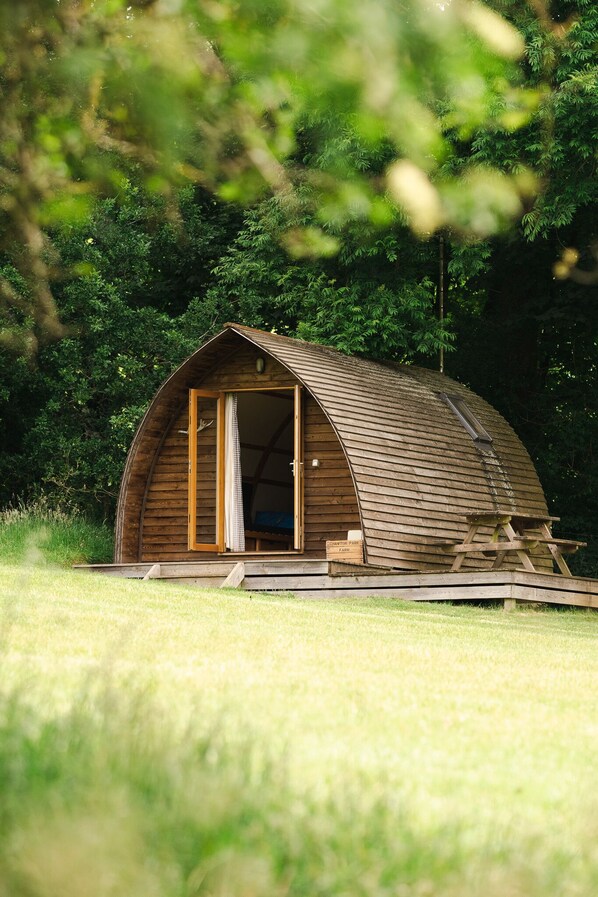 A wooden cabin with a curved roof, a large open doorway, and a small porch area.