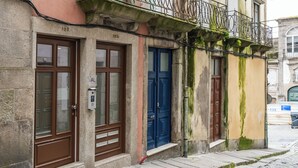 A building with numbered doors, a small step leading to the entrance, and a cobblestone street.