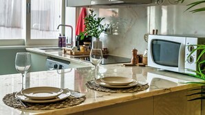 A kitchen with a microwave, a sink, and a window with blinds.
