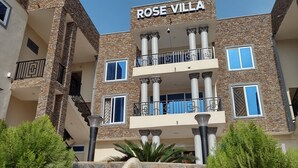 Um edifício de vários andares com fachada de pedra, varandas e uma placa com a inscrição "ROSE VILLA".