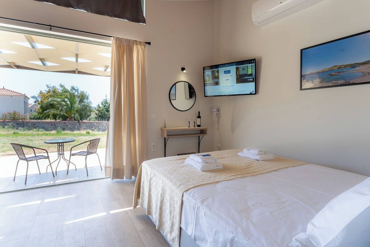 Habitación de hotel con cama, escritorio con computadora, silla y vista al exterior.