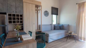 A modern living room with a wooden dining table, chairs, a sofa, and a small side table.