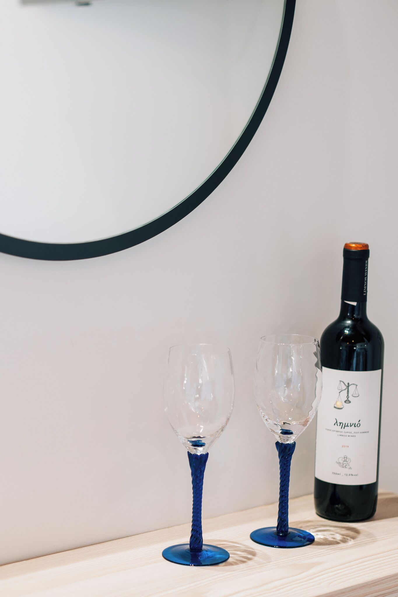 Duas taças de vinho sobre uma superfície de madeira, com uma garrafa de vinho ao lado.