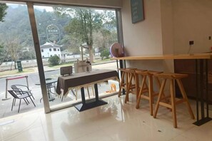 Een kamer met een groot raam, een houten tafel en een bar.