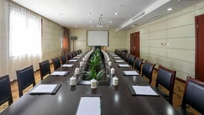 A conference room with a long table, chairs, a projector screen, and a plant. - Yandang Hotel (Wenzhou Teacher Education Institute Yandang) (Yueqing)