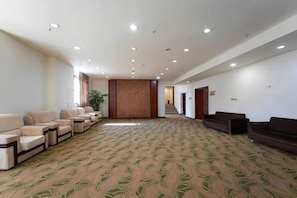 A spacious room with a patterned carpet, multiple seating areas, and a staircase leading to another level. - Yandang Hotel (Wenzhou Teacher Education Institute Yandang) (Yueqing)
