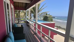 A covered outdoor seating area with a view of the beach and ocean. - The Whole Hibiscus - Pool & Ocean Front! (Utila)