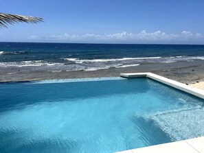 Piscina com vista para o oceano e uma linha costeira rochosa.
