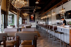A restaurant with a bar area, seating, and a chandelier.