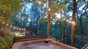 Un bain à remous dans une forêt, illuminé de guirlandes lumineuses.