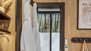 Une salle de bain moderne avec un mur en bois, une cabine de douche en verre et un porte-serviettes avec deux serviettes blanches.