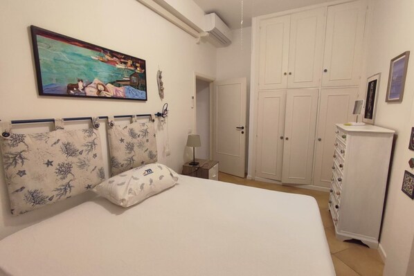 Une chambre à coucher comprenant un lit, une table de chevet, une commode, une armoire et un tableau accroché au mur.