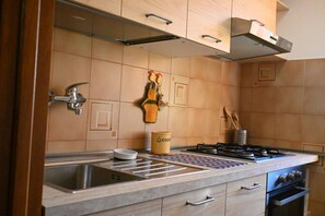 A kitchen with a stainless steel sink, a gas stove, wooden cabinets, and a coffee container.