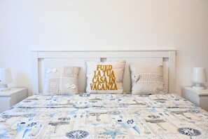 A bed with a patterned bedspread, a white headboard, and decorative pillows.