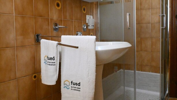 Baño con lavamanos, toallero y zona de ducha.