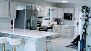 A modern kitchen with white cabinetry, stainless steel appliances, and a marble countertop.