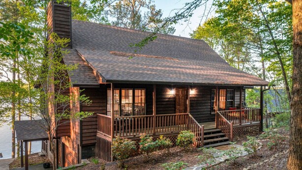 Une cabane rustique avec une façade en bois, une véranda avec des marches et une cheminée.