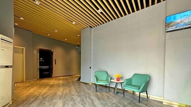 A modern lobby with a marble floor, a wooden slatted ceiling, and two green chairs with a small table. - Hotel Apartment (Shanghai National Convention and Exhibition Center Jiangqiao Old Street Branch) (Shanghai)
