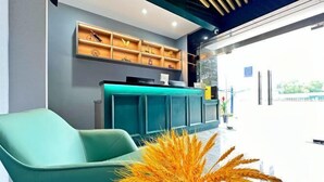 A teal sofa and a reception desk with a wooden shelf above. - Hotel Apartment (Shanghai National Convention and Exhibition Center Jiangqiao Old Street Branch) (Shanghai)