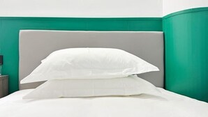A bed with white bedding and a grey headboard in a room with teal walls. - Hotel Apartment (Shanghai National Convention and Exhibition Center Jiangqiao Old Street Branch) (Shanghai)