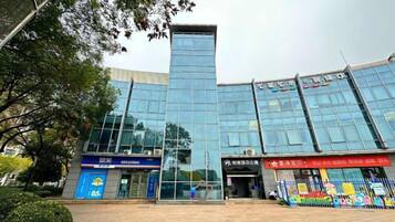 Um edifício moderno com fachada de vidro, estrutura vertical marcante e vitrine com sinalização.