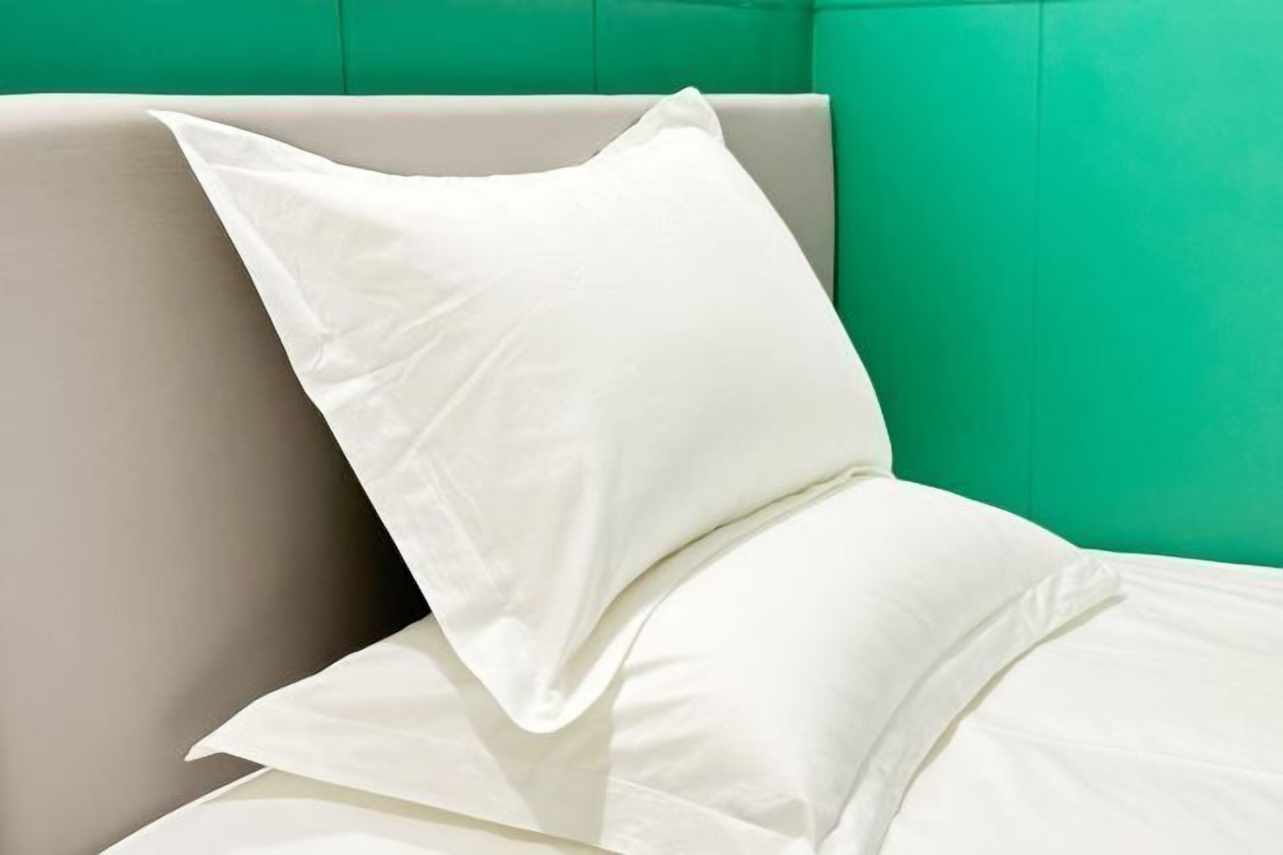A bed with white bedding and a green wall.