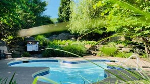 A swimming pool with a curved edge, surrounded by lush greenery and rocks. - Condo at Mtn Creek  sleep 4 Mountain view 1 Bdr 1 Bath #234 (Vernon Township)