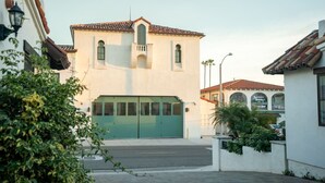A building with a green garage door, a white facade, and a tiled roof.