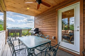 A covered patio with a table and chairs, a ceiling fan, and a sliding glass door leading to an outdoor seating area. - BryantPond Cabin-BNew Firepit! HotTub|Dog Friendly (Bryant Pond)