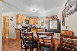 A kitchen with wooden cabinets, a granite countertop, and a refrigerator.