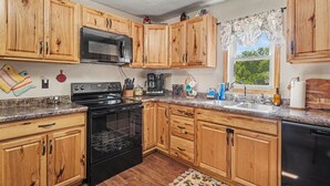 Una cocina con armarios de madera, microondas, estufa y pileta.