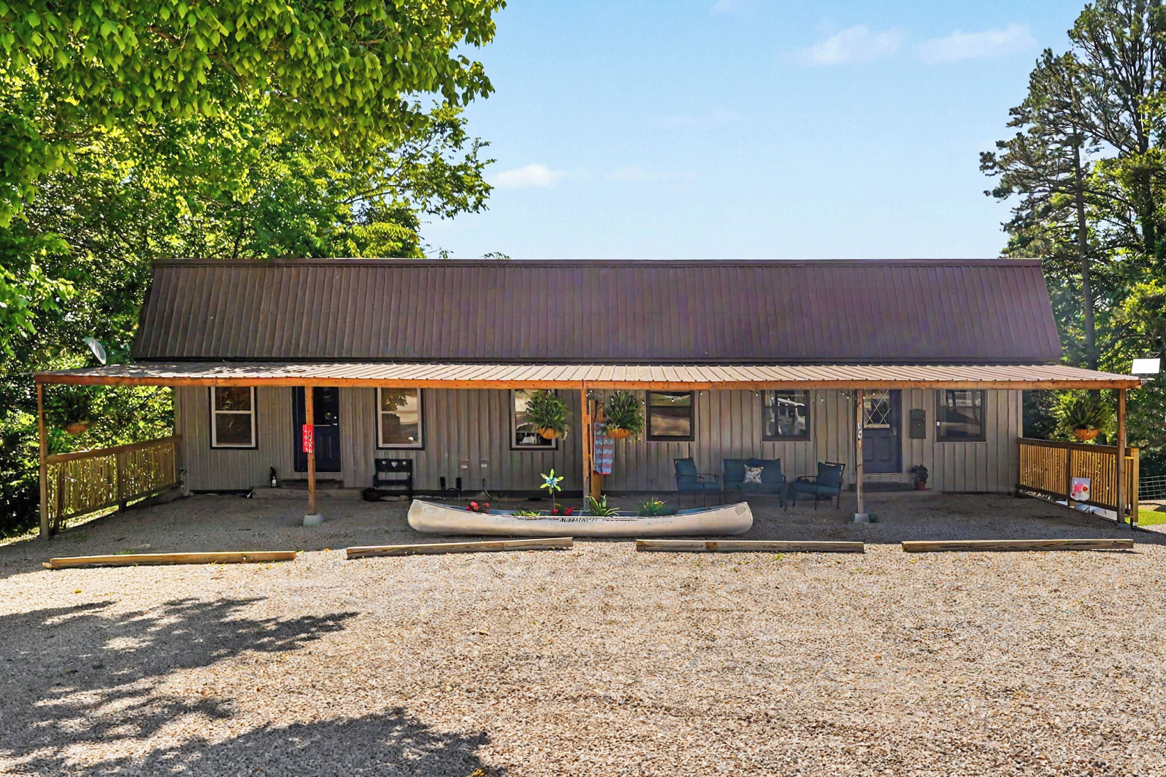 A building with a covered patio, a canoe, and outdoor seating.