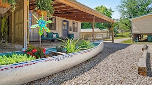 Un espacio al aire libre cubierto con una canoa, una estructura de madera y un sendero de grava.