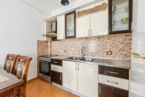 A compact kitchen with a stove, oven, sink, and cabinets.